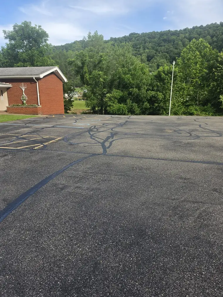 Gray, cracked parking lot beside a brick building before sealcoating