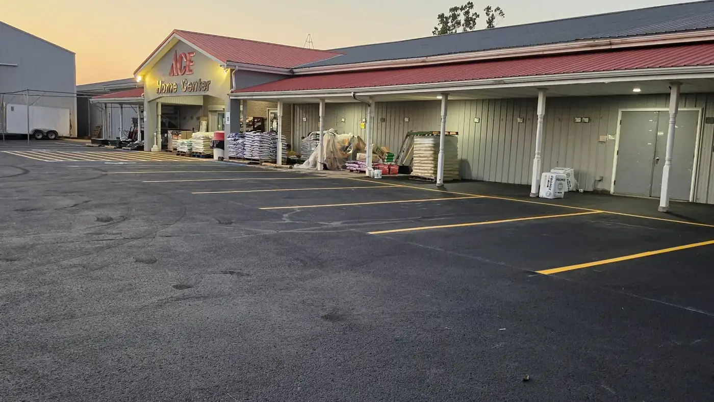 Freshly sealcoated store parking lot with new yellow stall lines at dusk, striped by Leek's of New Martinsville, WV